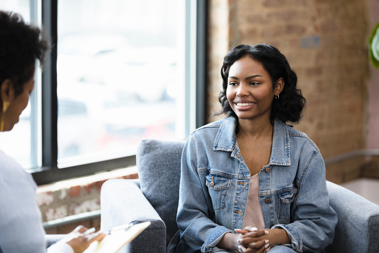 The young woman smiles at her doctor while she receives some positive news.