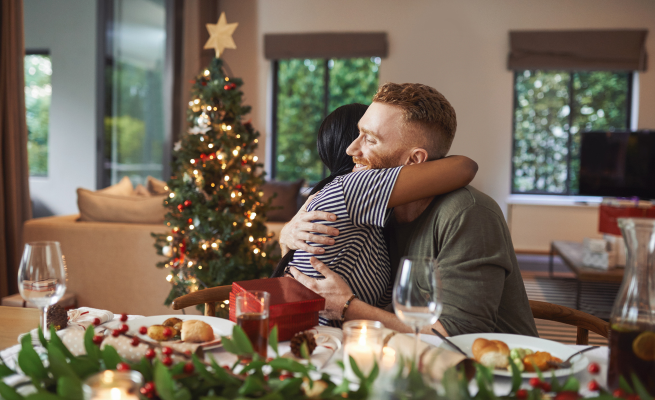 Shot of young friends opening their gifts together while having Christmas lunch at home