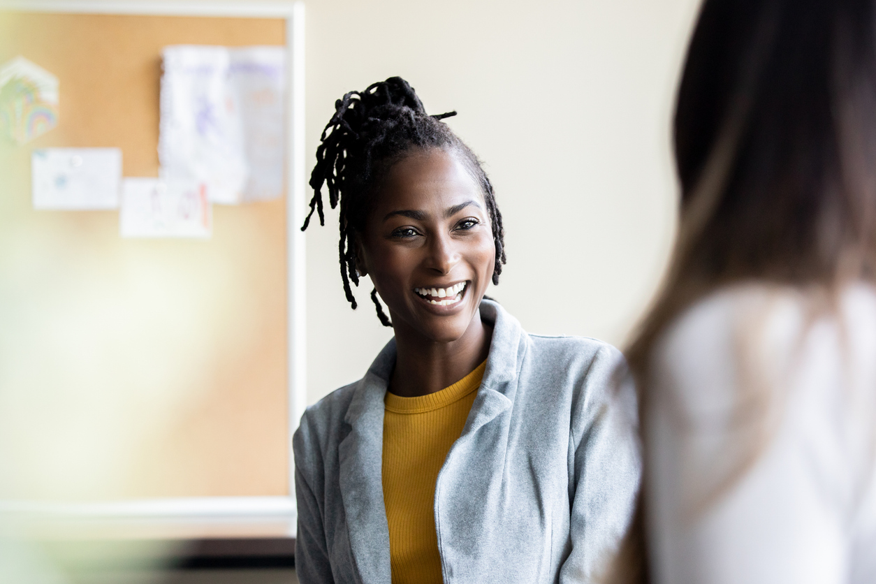 A high school instructor, who is a woman, oversees a group discussion with her students