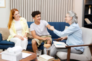 Smiling teenage boy giving fist bump with his therapist after a successful therapy session with his mother sitting next to him