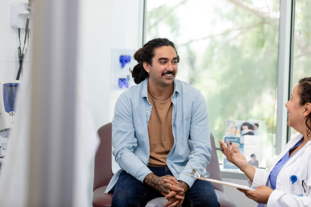 male patient sitting in a chair listening to a doctor