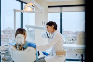 A dentist smiles at a patient while caring for their teeth after overcoming depression in dentists
