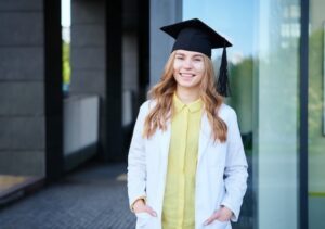 A graduate wearing their cap and gown and smiling after beating new grad depression
